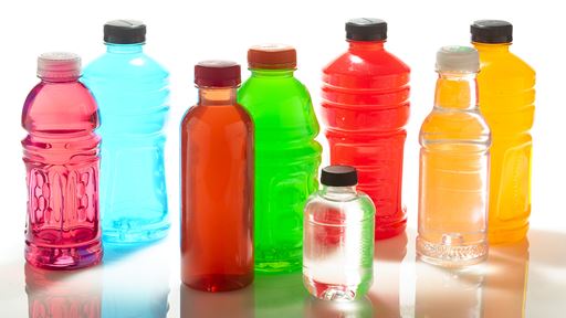 Eight various bottles of different beverages in several different colors and spaced out in a line side by side.
