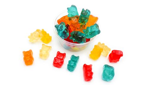 Gummy bears overflowing from a ramekin and laid throughout the image.
