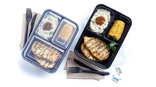 A prepared ready to eat meal of grilled chicken, mashed potatoes and corn on the cobb all  in a container with plastic silver ware on the side of the container.