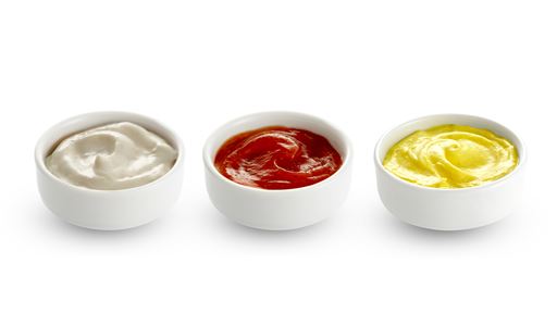 Three shallow white circular ramekins filled with three different sauces on a white background.