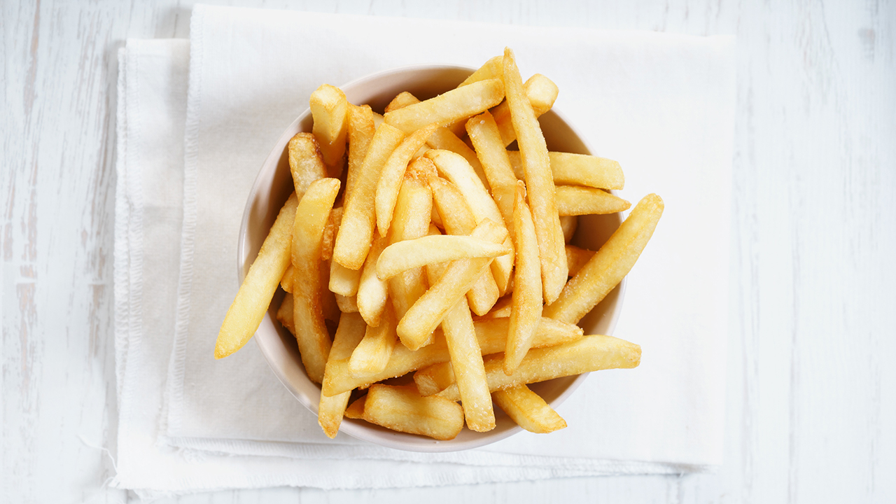 A circular container filled with crispy golden French fries placed on top of a white napkin.