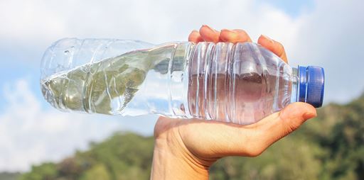 Hand holding plastic water bottle horizontally. 