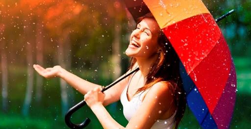 Laughing woman in light rain with colorful umbrella.