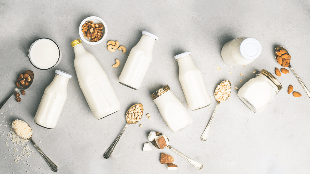 Wide array of dairy and non-dairy milks laid out next to their corresponding ingredient base, such as cashews, almonds, and coconut.