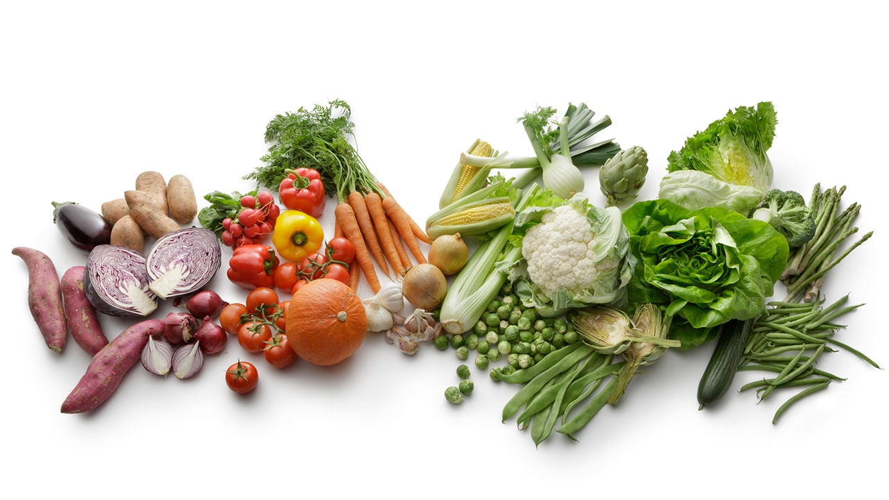 Variety of fruits and vegetables laid out organized in a gradient from light purple all the way to green on the other end.