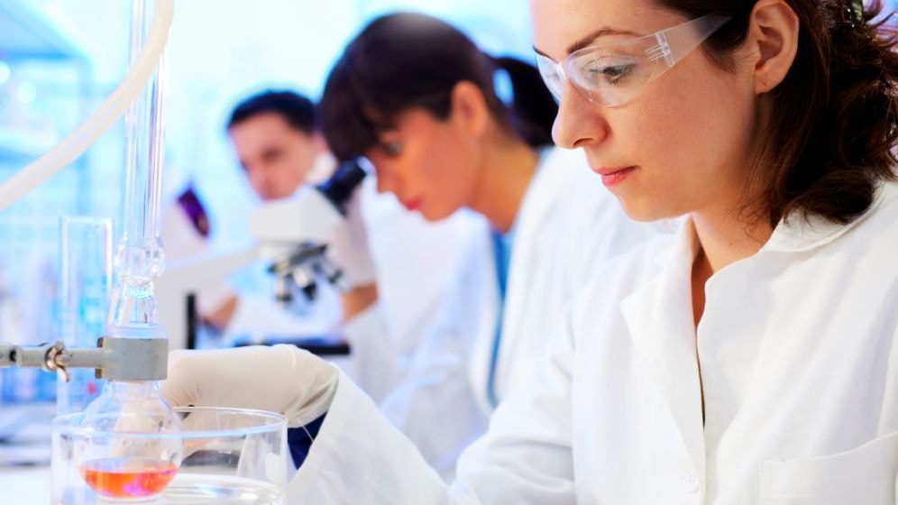 Scientists in lab working with beakers and microscopes.