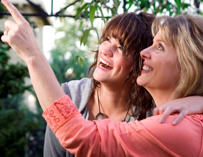 Smiling women looking to sky surrounded by plants.