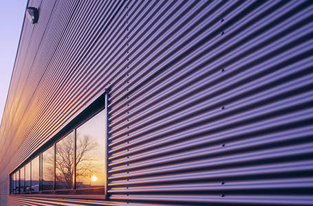 Modern glass and metal building reflecting sunset.
